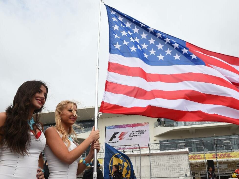 Zwei Frauen posieren mit der US-Flagge in der Formel-1-Startaufstellung